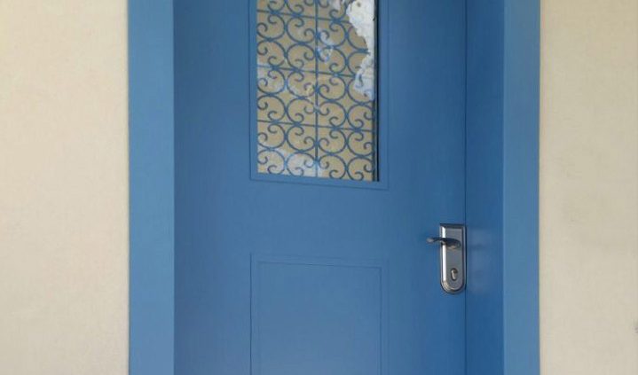 דלת כניסה כחולה עם חלון סורג מעוצב צבוע בגוון הדלת